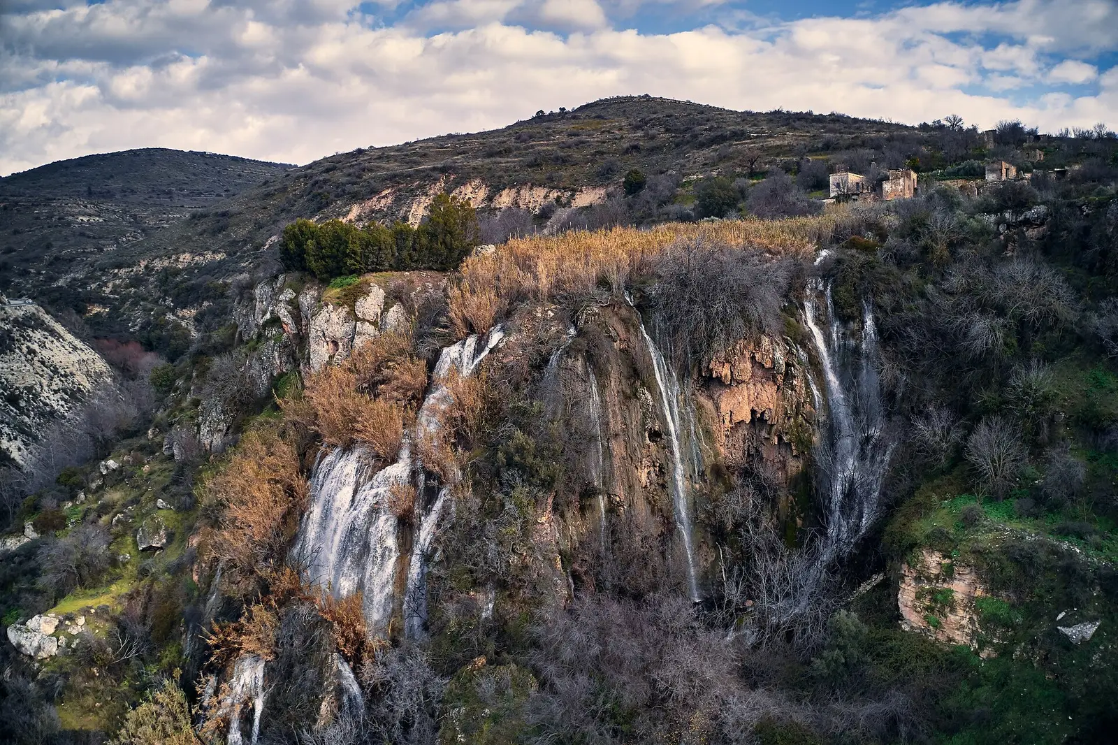 Water cascading over mossy rock ledges through a green Cyprus forest ravine