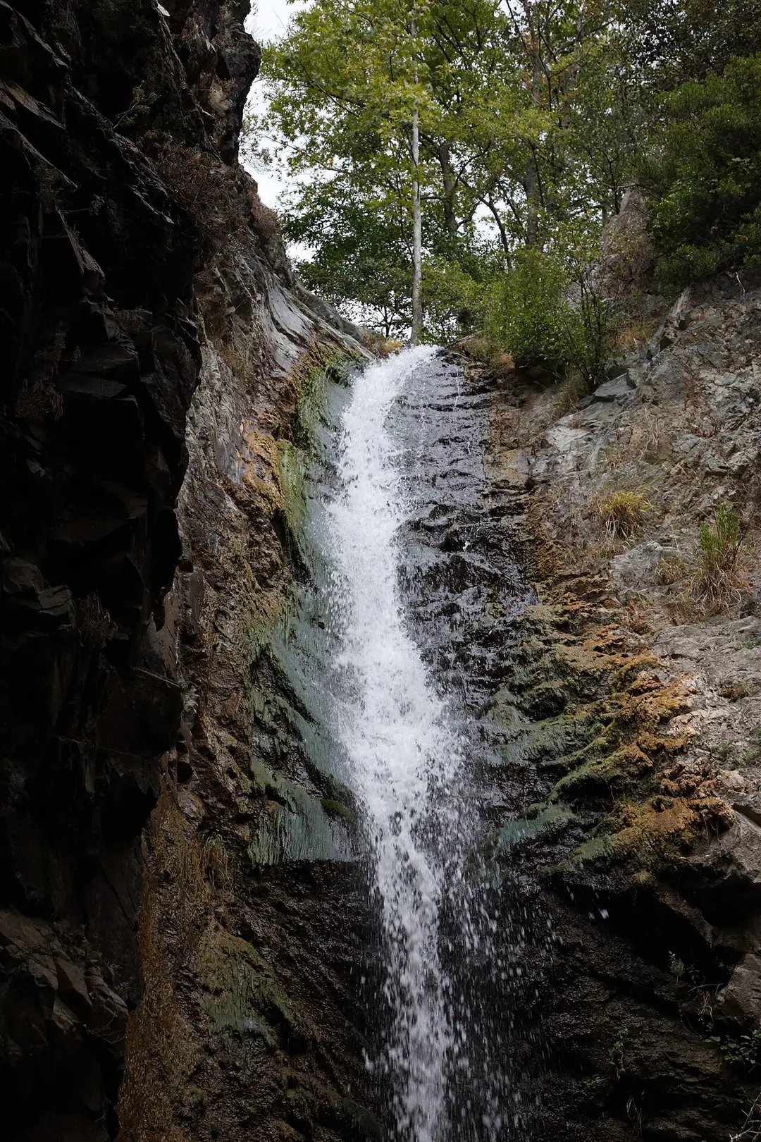 The tall single-drop Millomeris waterfall falling into a pool below a limestone cliff